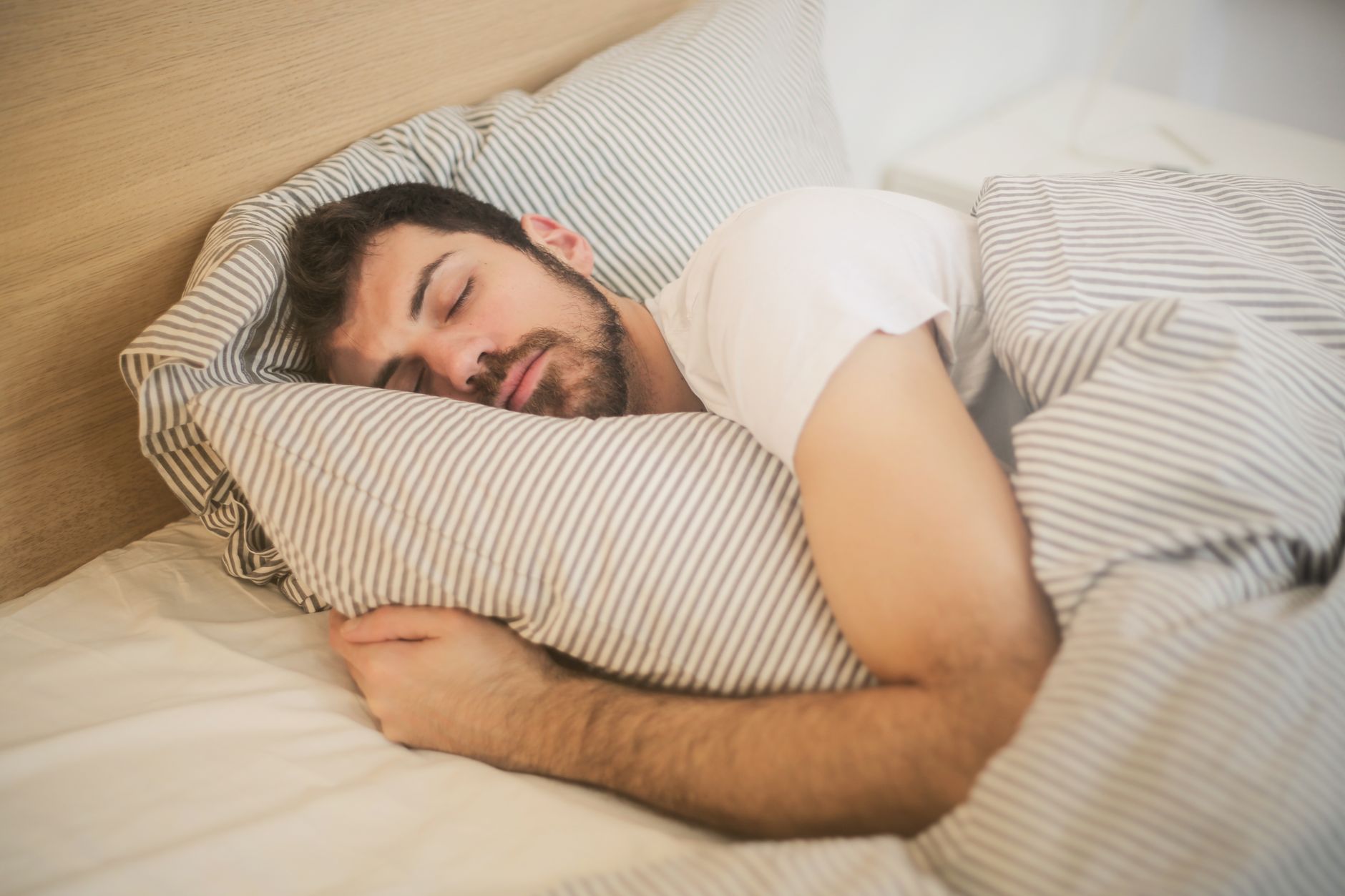 Seseorang tidur nyenyak di tempat tidur nyaman sebagai trik tidur berkualitas agar segar saat bangun.