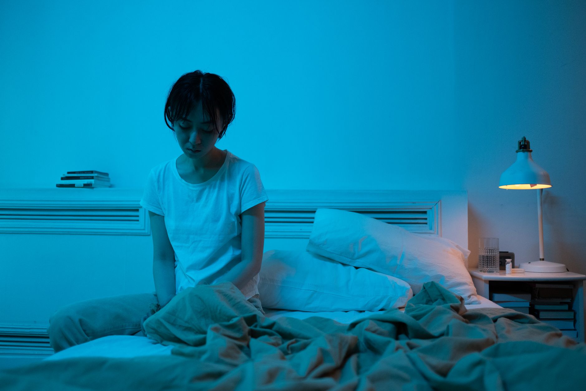 Illustrasi orang sulit tidur karena overthinking di tempat tidur, dengan teks tips mengatasi kecemasan tidur.