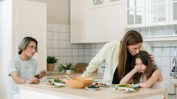 Seorang anak terlihat sedih sedang ditenangkan orang tuanya di dapur sebagai ilustrasi dampak parentification.