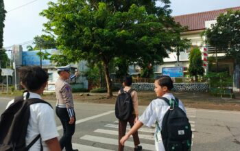 Personel Sat Lantas Polres Bima Kota Bantu Anak Sekolah Menyeberang Jalan