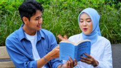 Seseorang sedang membaca buku fisik untuk mengurangi kecanduan HP.