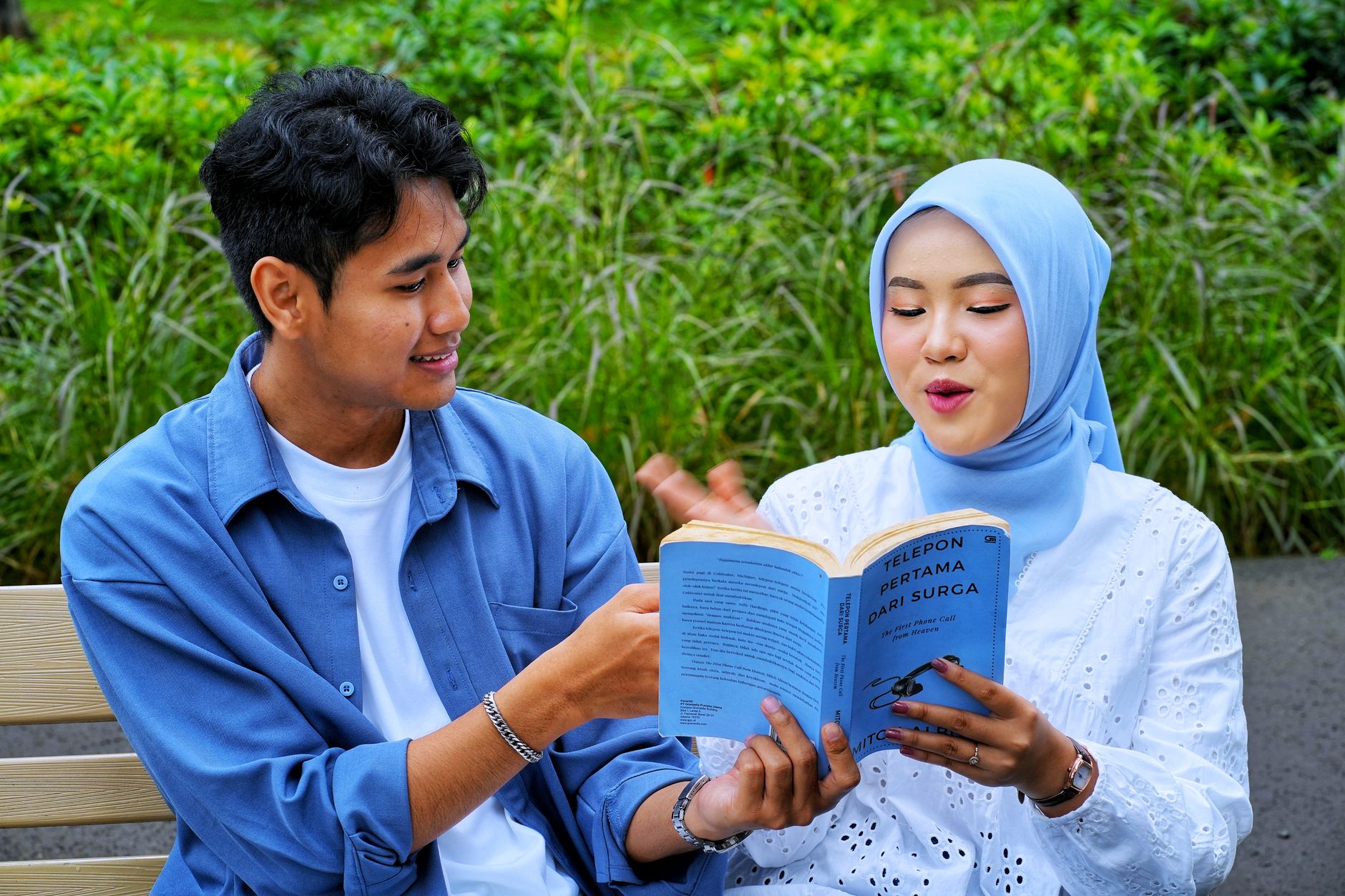 Seseorang sedang membaca buku fisik untuk mengurangi kecanduan HP.