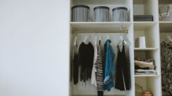 Rapi deretan pakaian netral di lemari, mengilustrasikan konsep minimalist wardrobe.