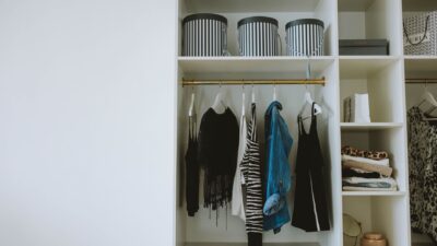 Rapi deretan pakaian netral di lemari, mengilustrasikan konsep minimalist wardrobe.