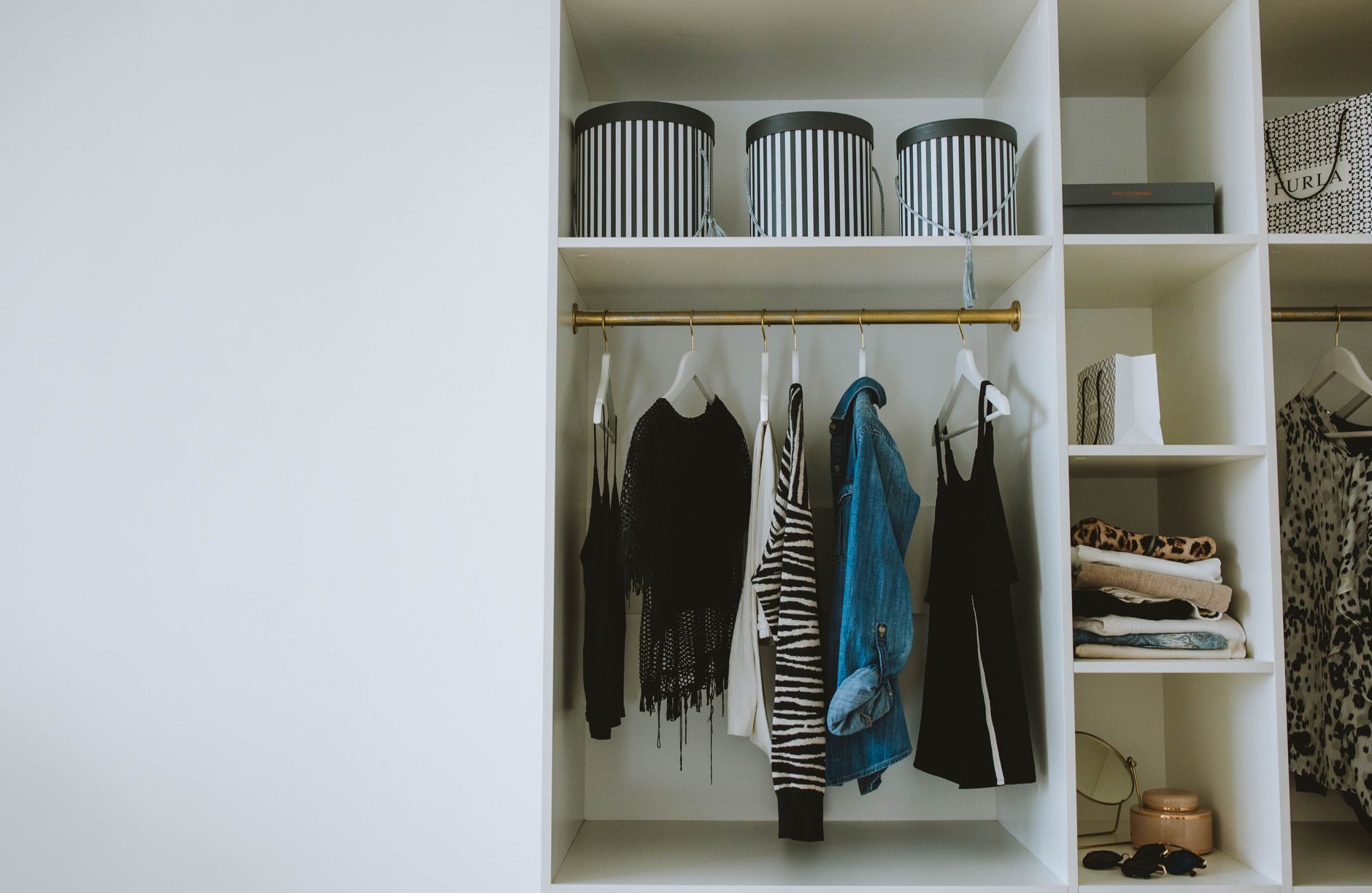 Rapi deretan pakaian netral di lemari, mengilustrasikan konsep minimalist wardrobe.