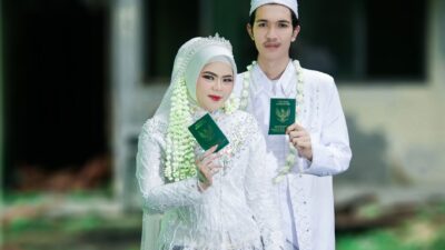 Pengantin mengenakan busana tradisional mewah dalam prosesi pernikahan adat Indonesia.