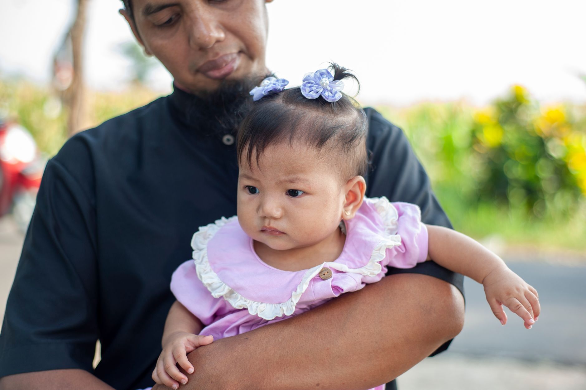 Seorang ayah tersenyum bahagia sambil menggendong anak perempuannya dengan penuh kasih sayang.