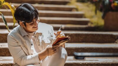 Seseorang sedang menulis jurnal di meja untuk menenangkan pikiran yang gelisah.