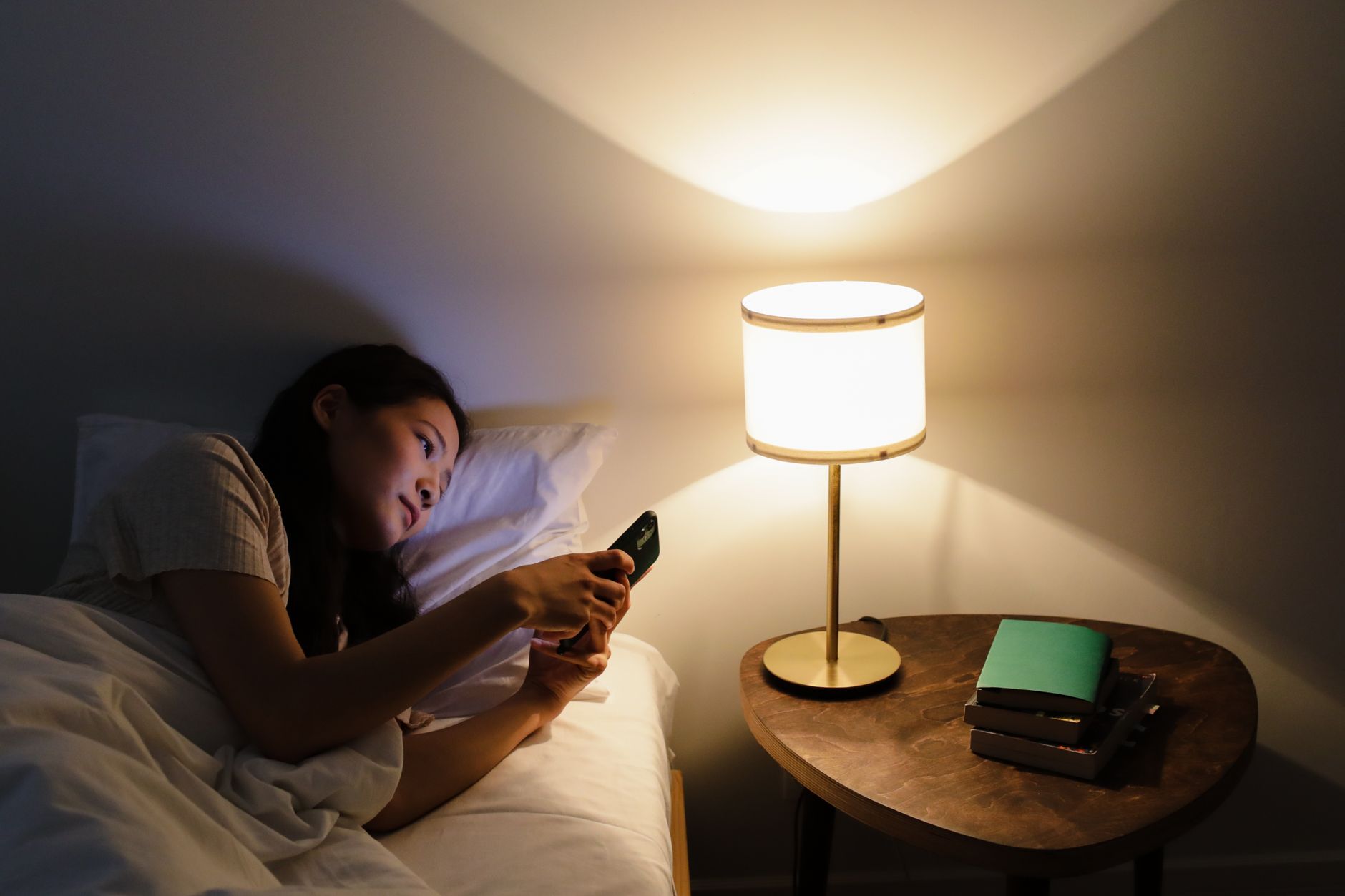 Seseorang memegang smartphone di tempat tidur saat bangun pagi.