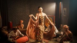 Anak muda merenung sambil mendengarkan musik tradisional Indonesia dengan headphone, menggambarkan krisis identitas budaya.