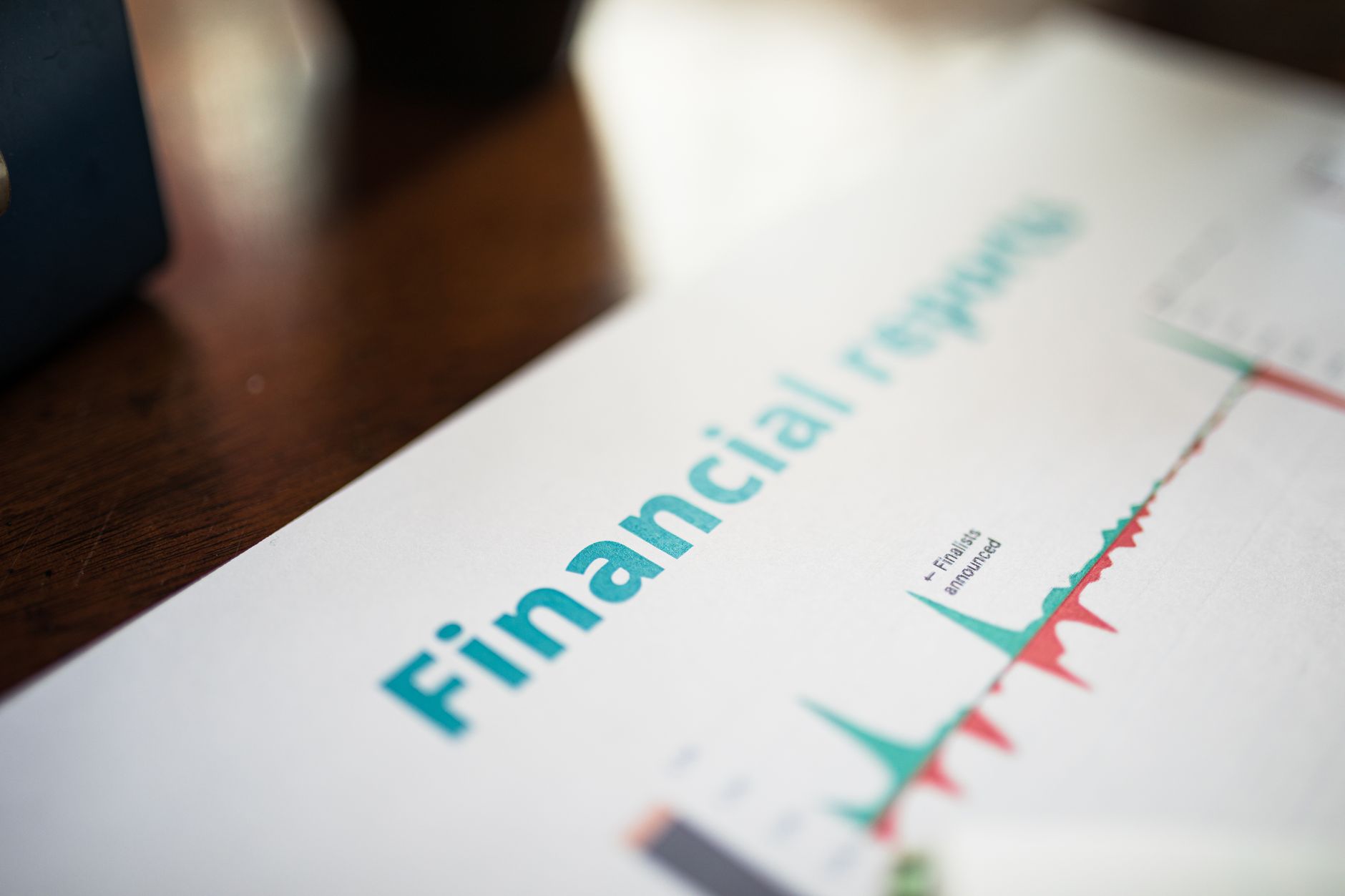 Seseorang menganalisis grafik dan data laporan finansial perusahaan di atas meja kerja.