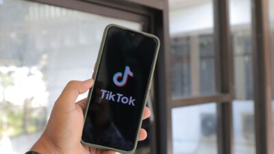 Ilustrasi smartphone dengan ikon TikTok dan panah yang menunjukkan cara kerja algoritma FYP TikTok.