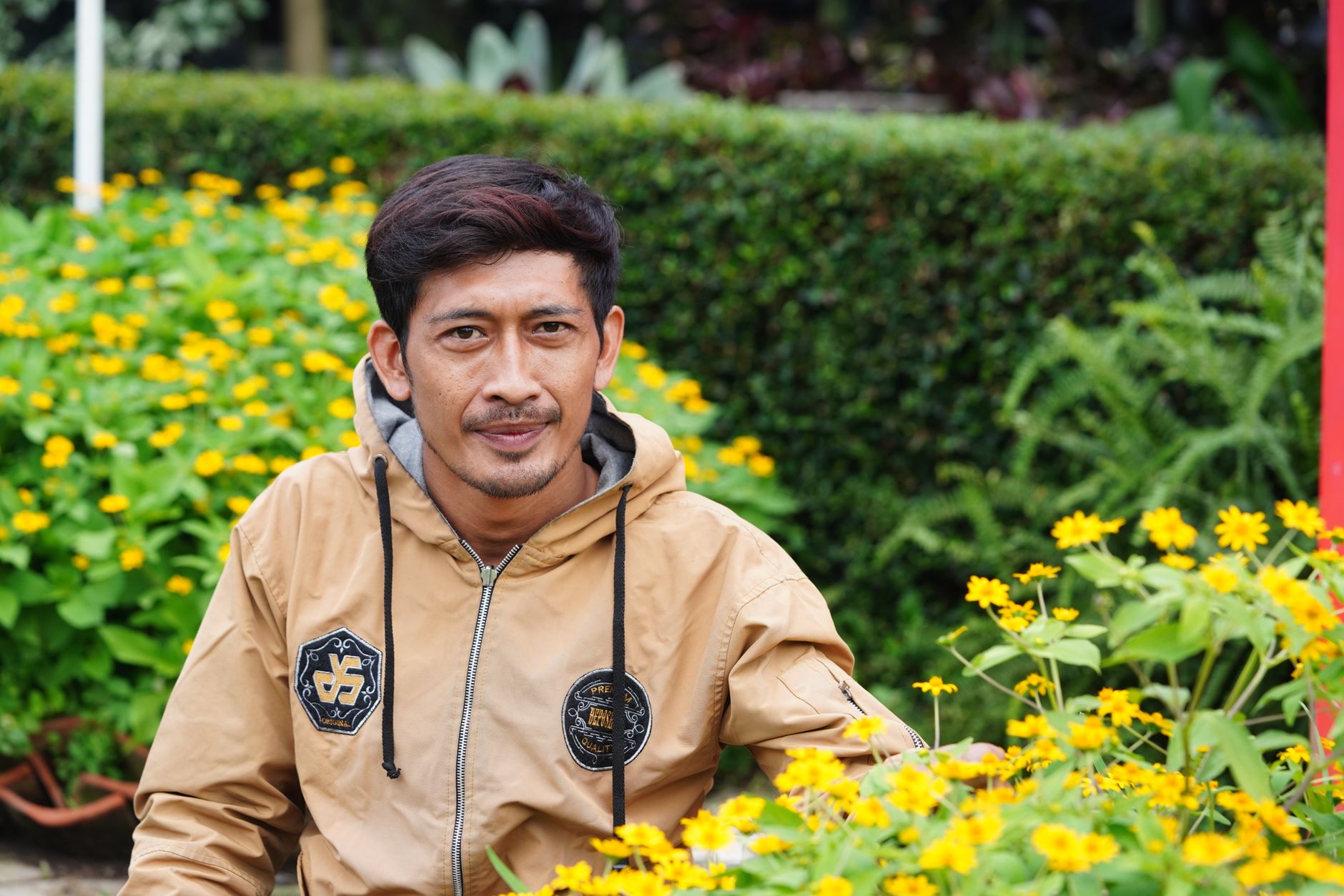 Pria dewasa tersenyum percaya diri dengan latar belakang modern, merepresentasikan karisma dan daya tarik.