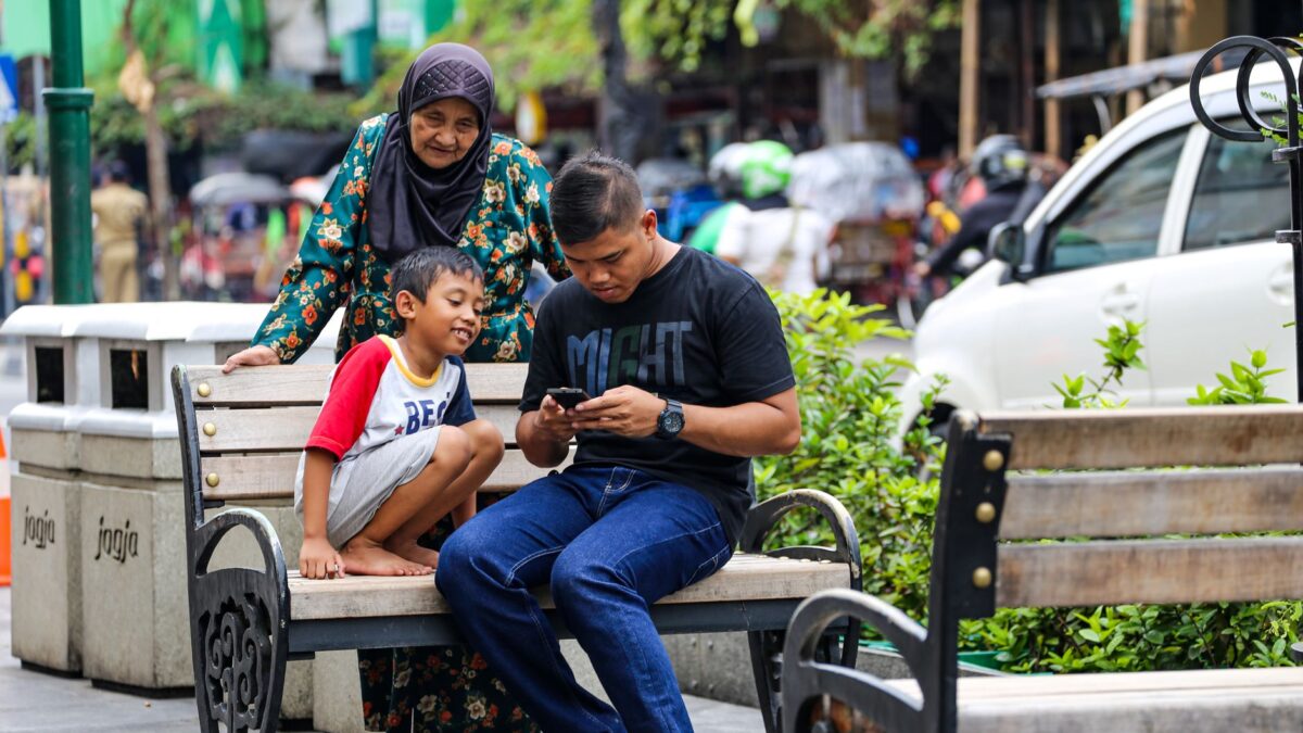 Ayah yang sibuk dengan ponselnya duduk bersama keluarga di Malioboro, Yogyakarta.