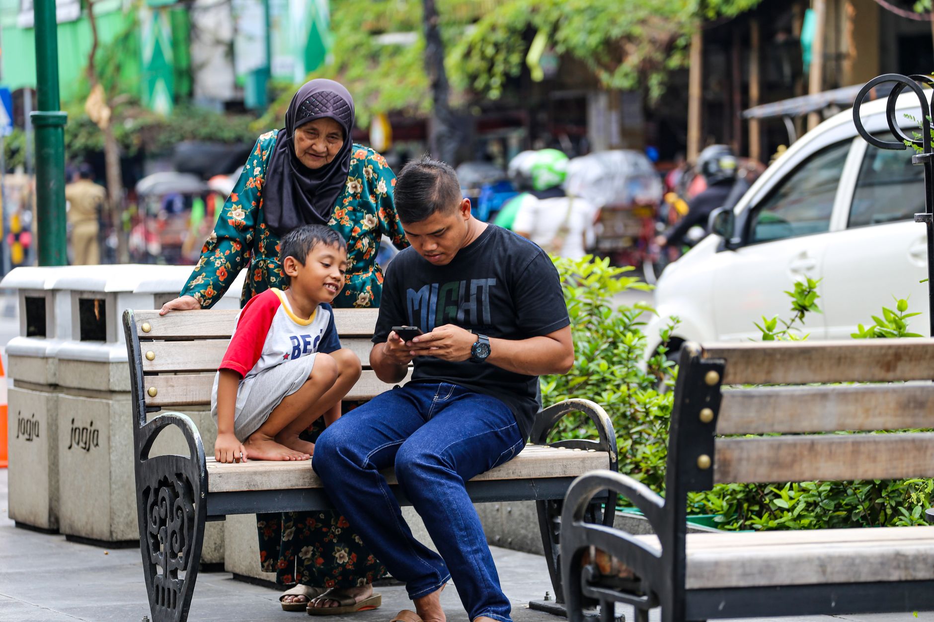 Ayah yang sibuk dengan ponselnya duduk bersama keluarga di Malioboro, Yogyakarta.