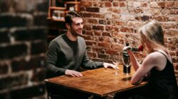 A couple smiling across a table during a romantic date at a cozy restaurant.