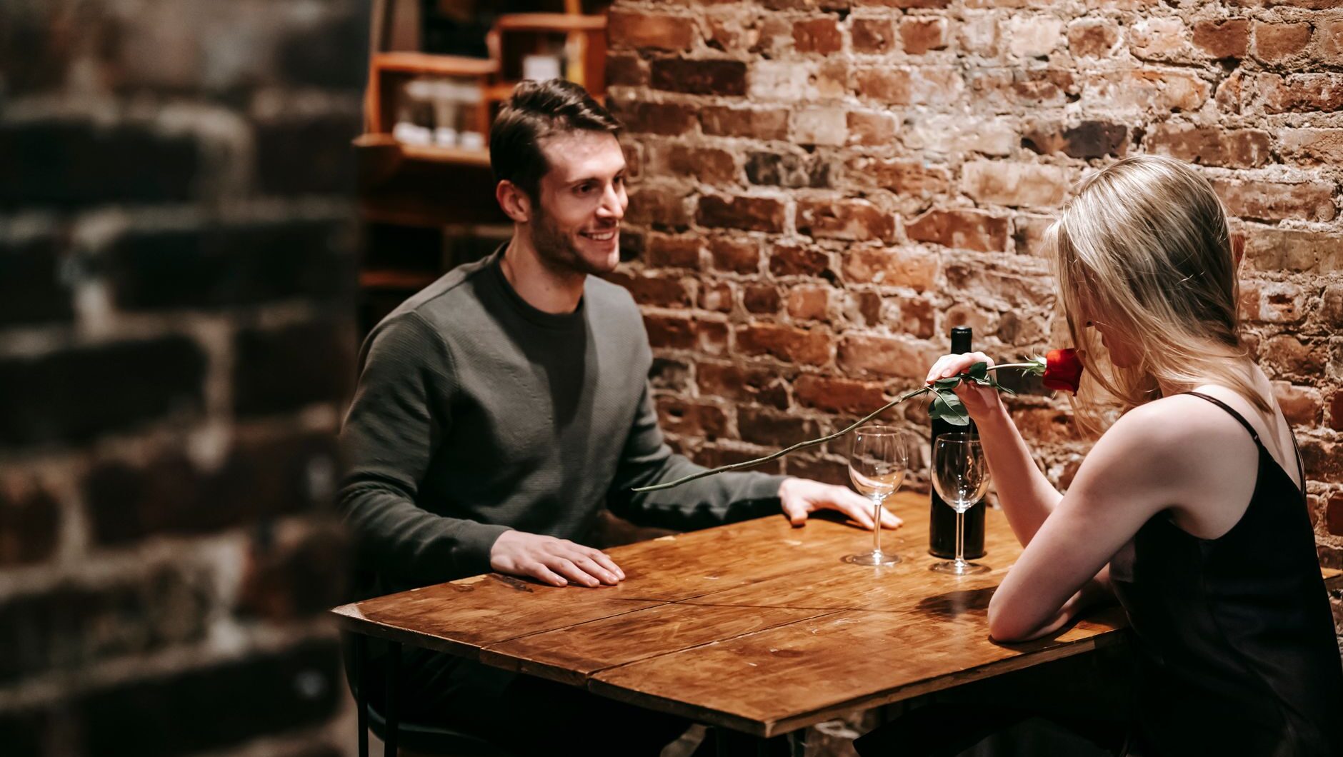 A couple smiling across a table during a romantic date at a cozy restaurant.