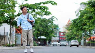 Pria mengenakan kemeja biru muda dan celana khaki untuk gaya busana pria yang timeless di jalan kota.