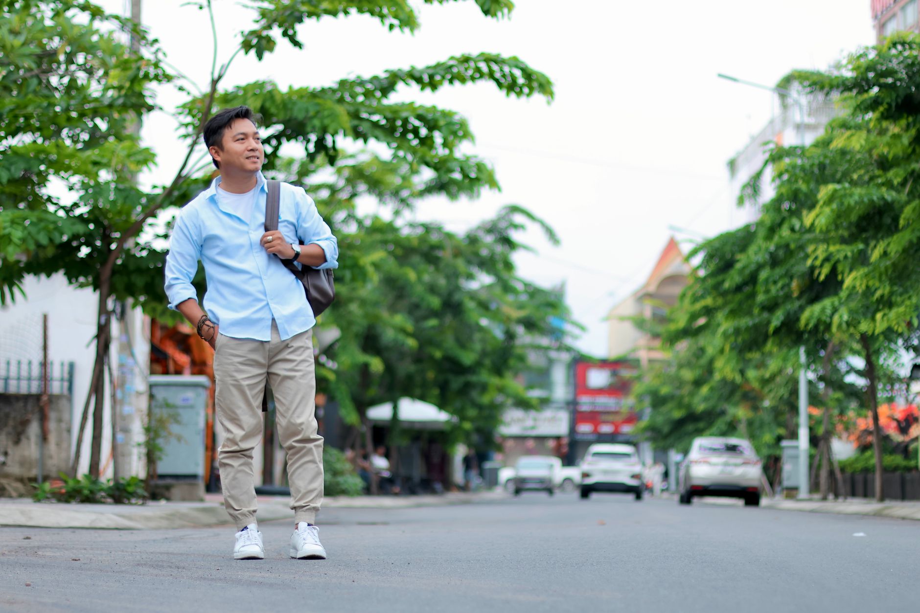 Pria mengenakan kemeja biru muda dan celana khaki untuk gaya busana pria yang timeless di jalan kota.