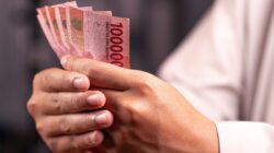 Seseorang menghitung uang pecahan Rupiah sebagai bagian dari penerapan prinsip keuangan.