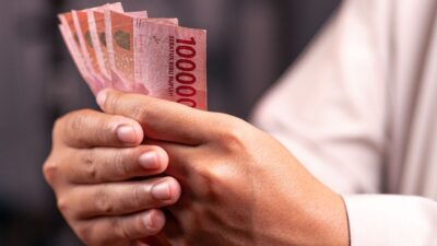 Seseorang menghitung uang pecahan Rupiah sebagai bagian dari penerapan prinsip keuangan.