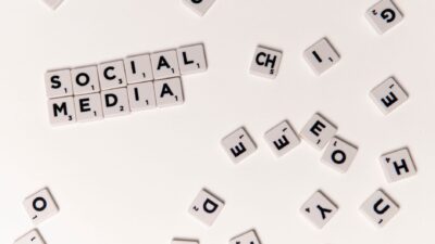 Scrabble tiles spelling "SOCIAL MEDIA" on a white background, surrounded by scattered letter tiles.