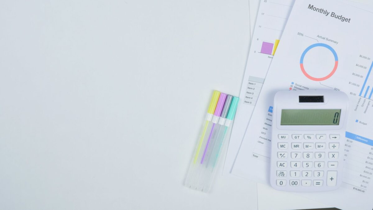 A calculator, colorful markers, and financial reports on a desk for Zero Based Budgeting.