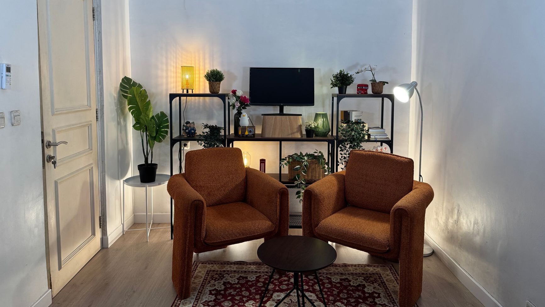 Cozy minimalist living room interior showcasing comfortable penataan rumah with armchairs and shelving.