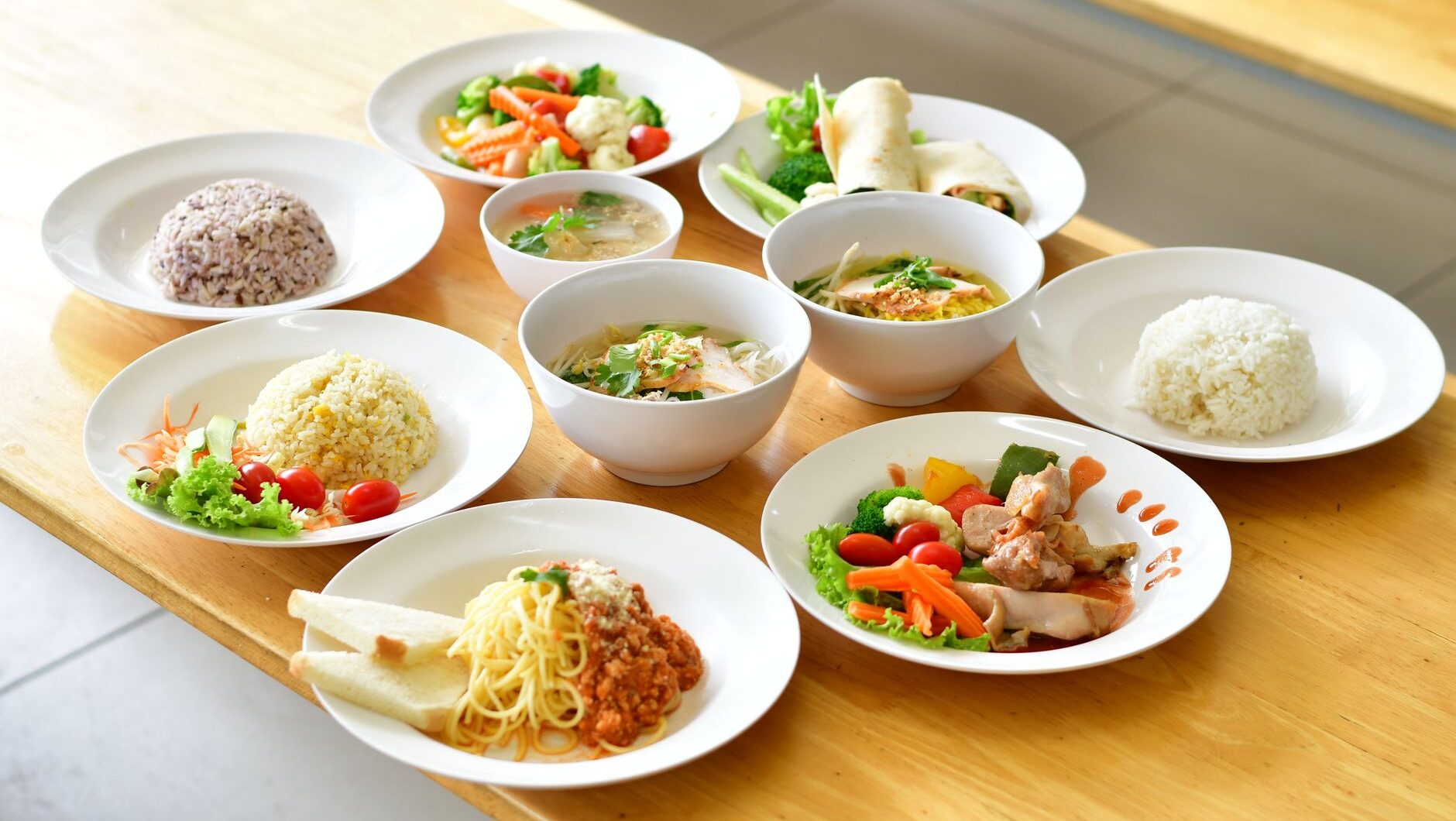 Berbagai hidangan makanan sehat tertata di atas meja kayu.