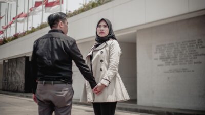 A young couple holding hands outside, signaling a potential krisis hubungan.