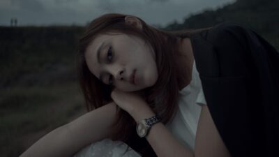 Moody portrait of a young woman resting her head on her hand outdoors, illustrating the topic of Tipe Wanita Toksik.