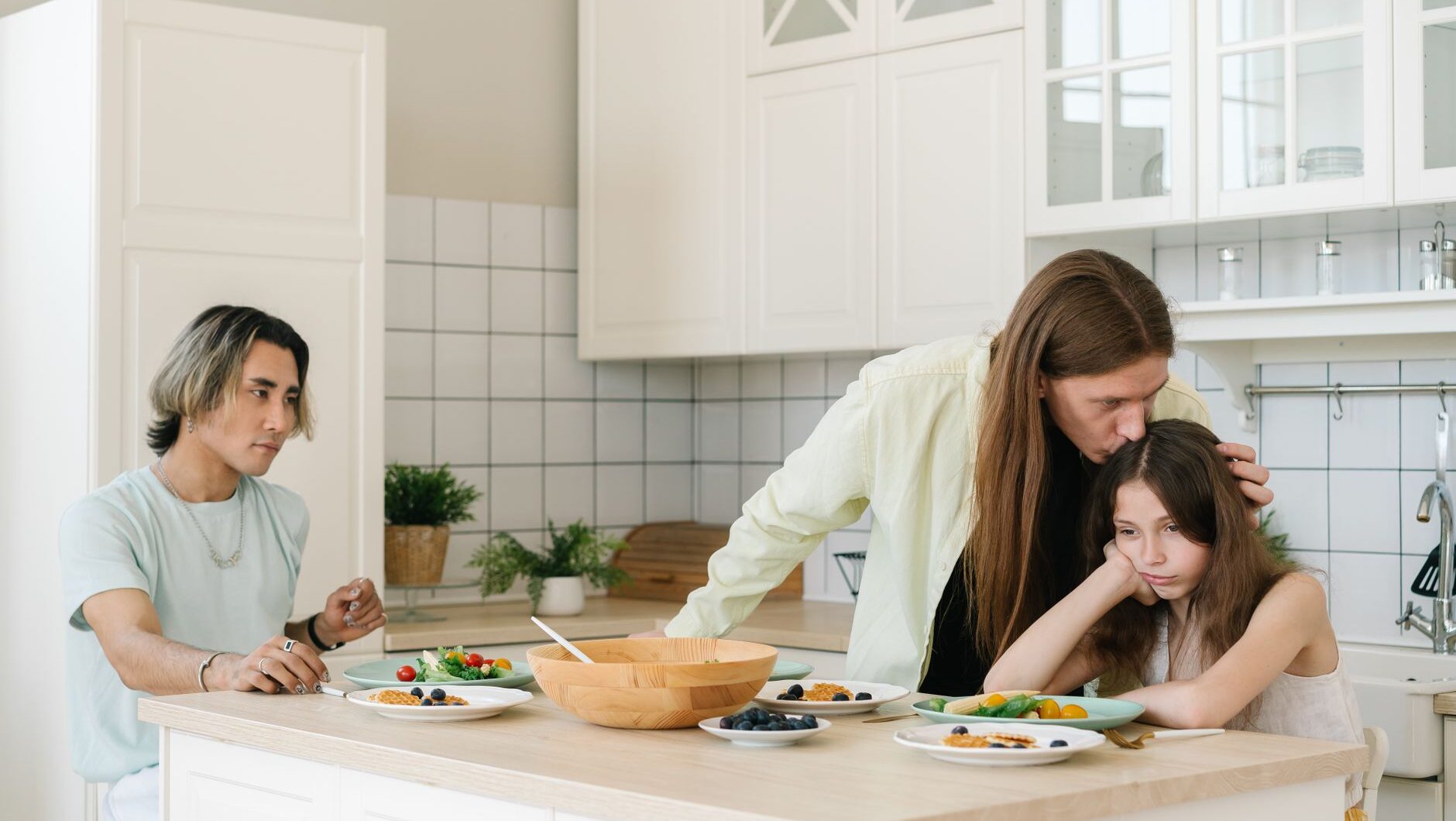 Seorang anak terlihat sedih sedang ditenangkan orang tuanya di dapur sebagai ilustrasi dampak parentification.