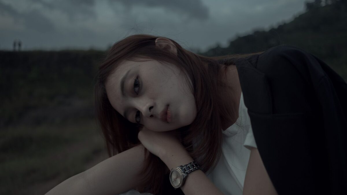 A young woman with long hair rests her head on her hand, showing a sign a woman does not like you.