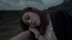 A young woman with long hair rests her head on her hand, showing a sign a woman does not like you.