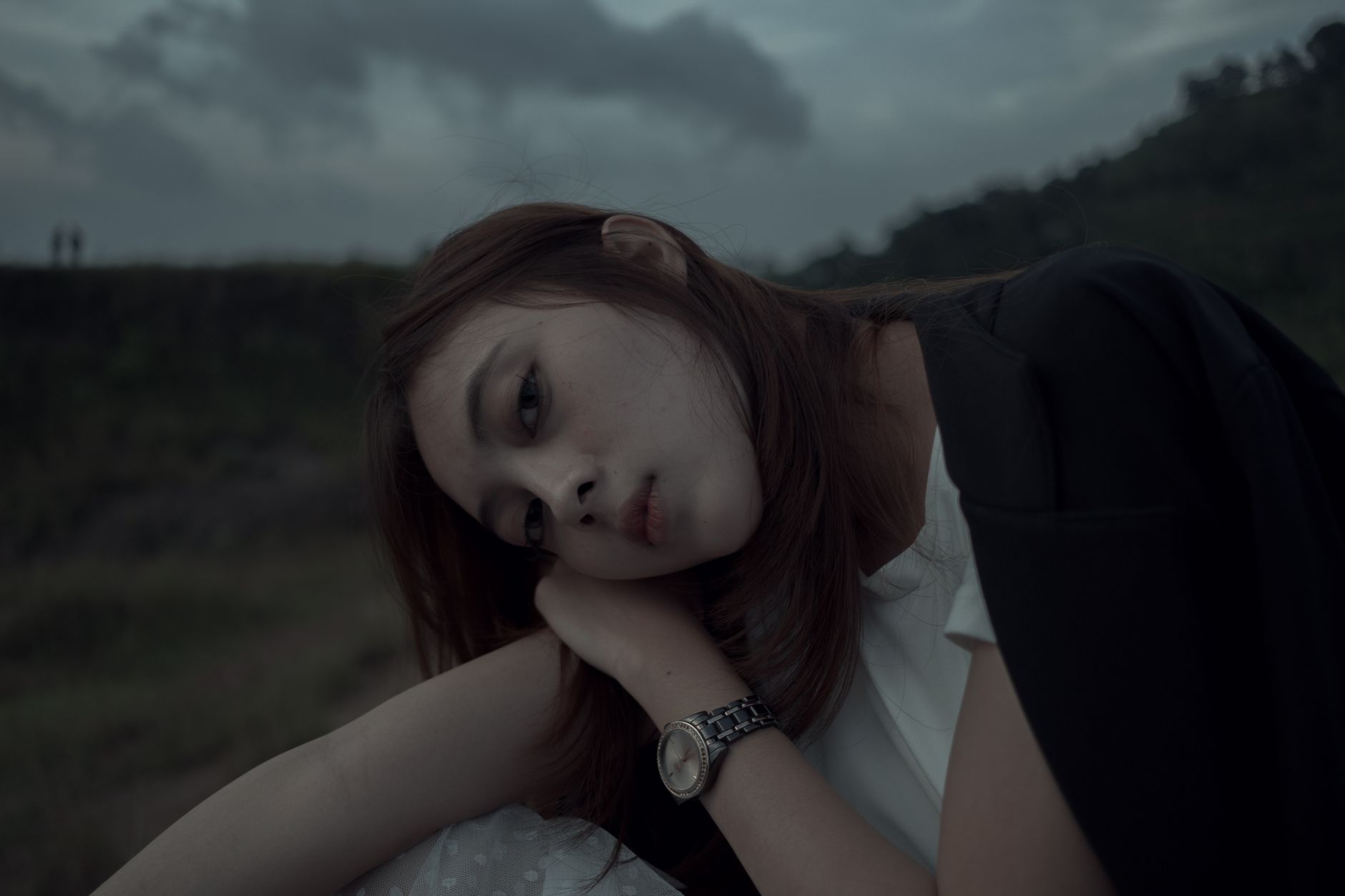 A young woman with long hair rests her head on her hand, showing a sign a woman does not like you.