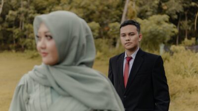 Seorang pria berjas dan wanita berhijab berpose di alam terbuka, membahas alasan pasangan balikan mantan.