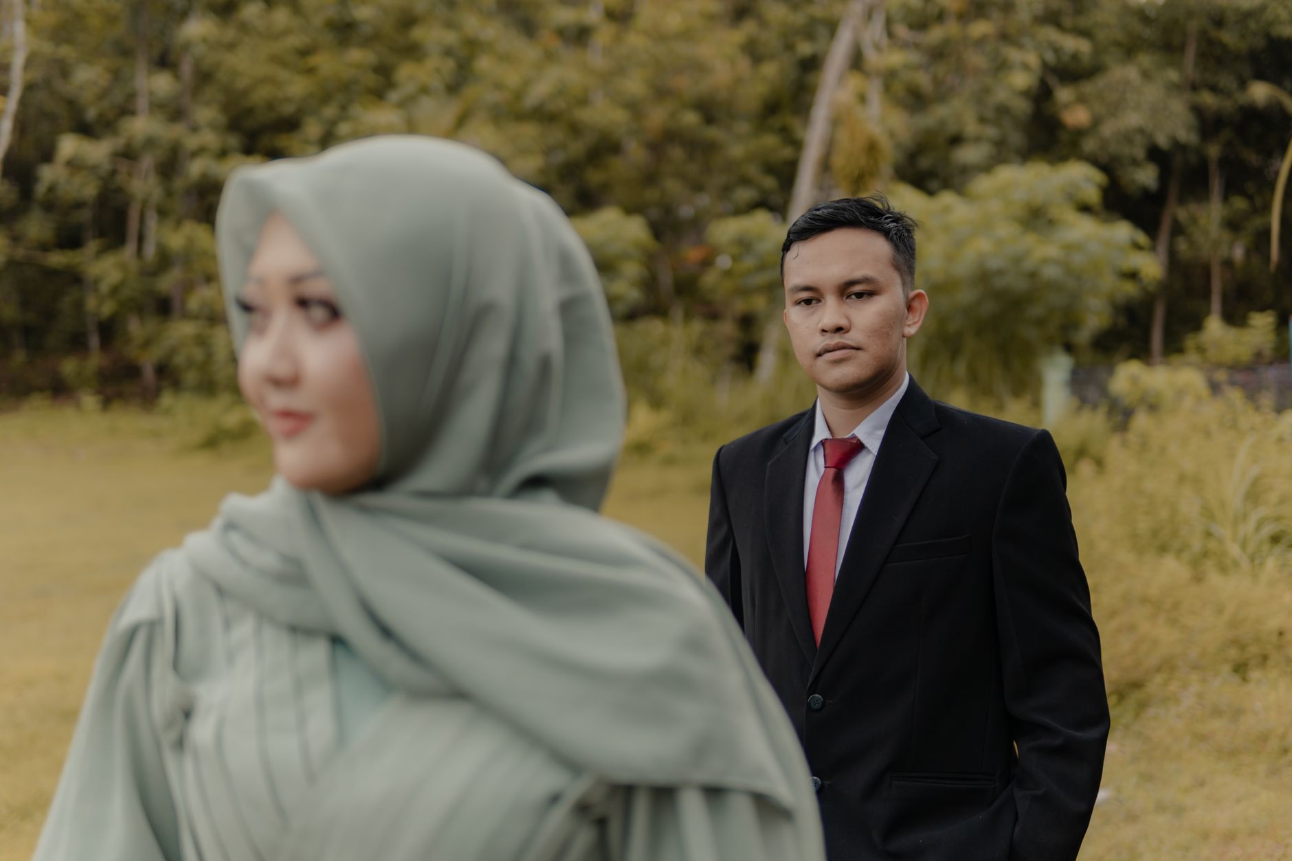 Seorang pria berjas dan wanita berhijab berpose di alam terbuka, membahas alasan pasangan balikan mantan.