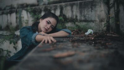 A distressed young woman in a denim jacket rests her chin on her hands, struggling with how to sulit melupakan mantan.