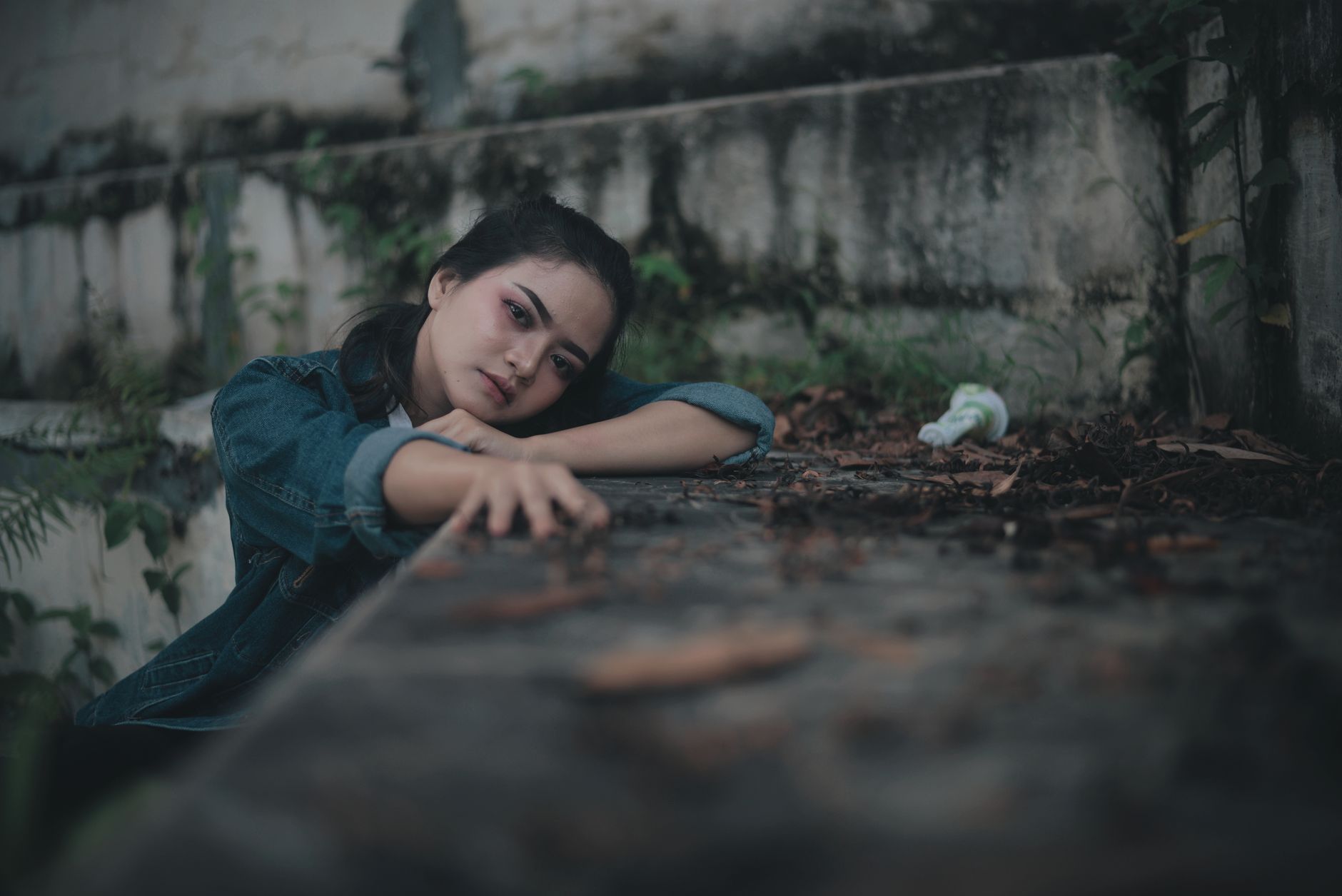 A distressed young woman in a denim jacket rests her chin on her hands, struggling with how to sulit melupakan mantan.