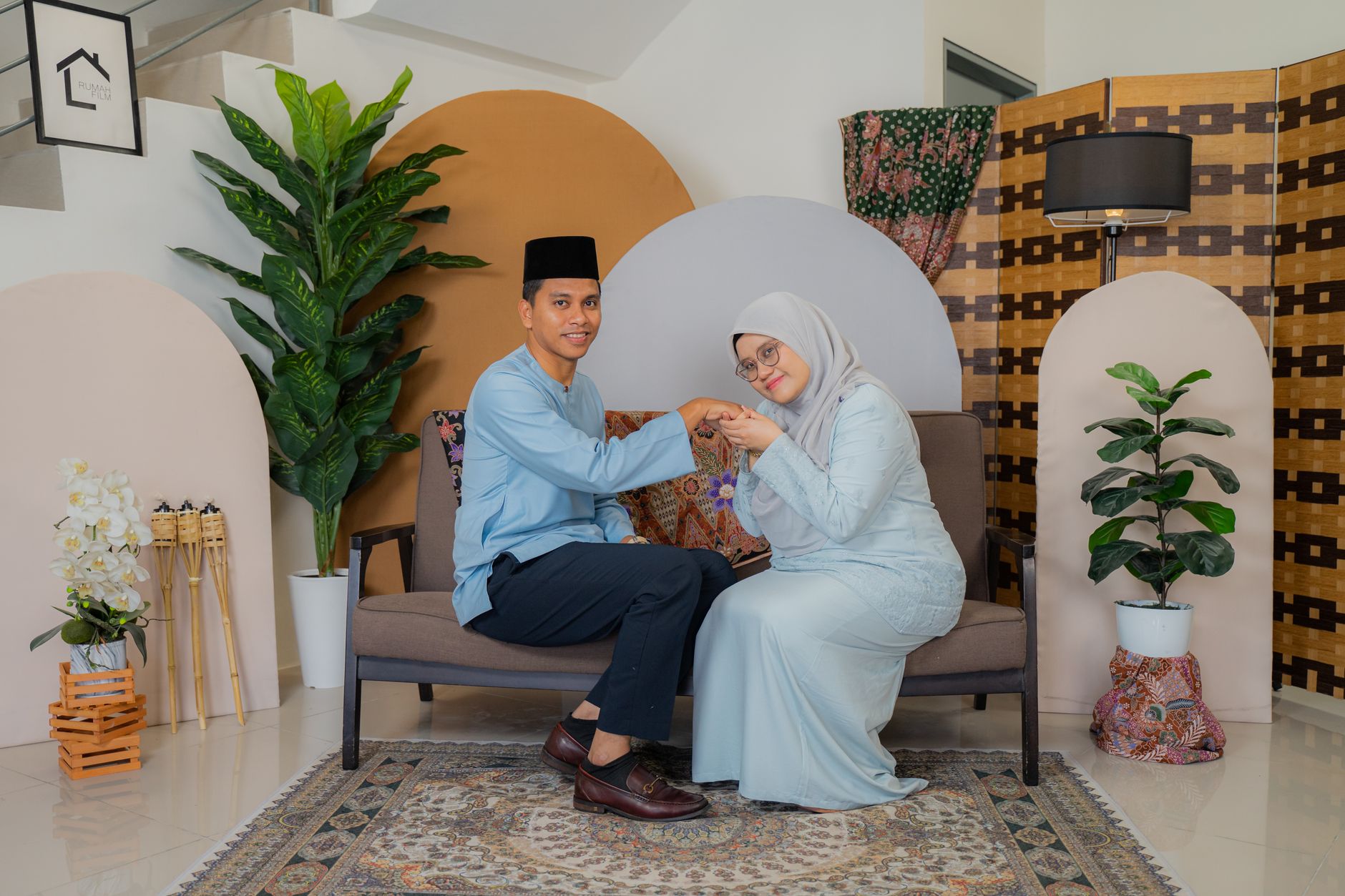 A young man holding a woman's hand to put a ring on her finger while sitting on a couch.