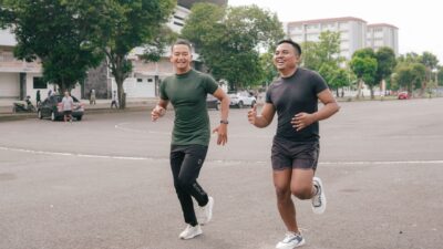 Dua pria sedang melakukan olahraga ringan dengan cara jogging bersama di area outdoor.