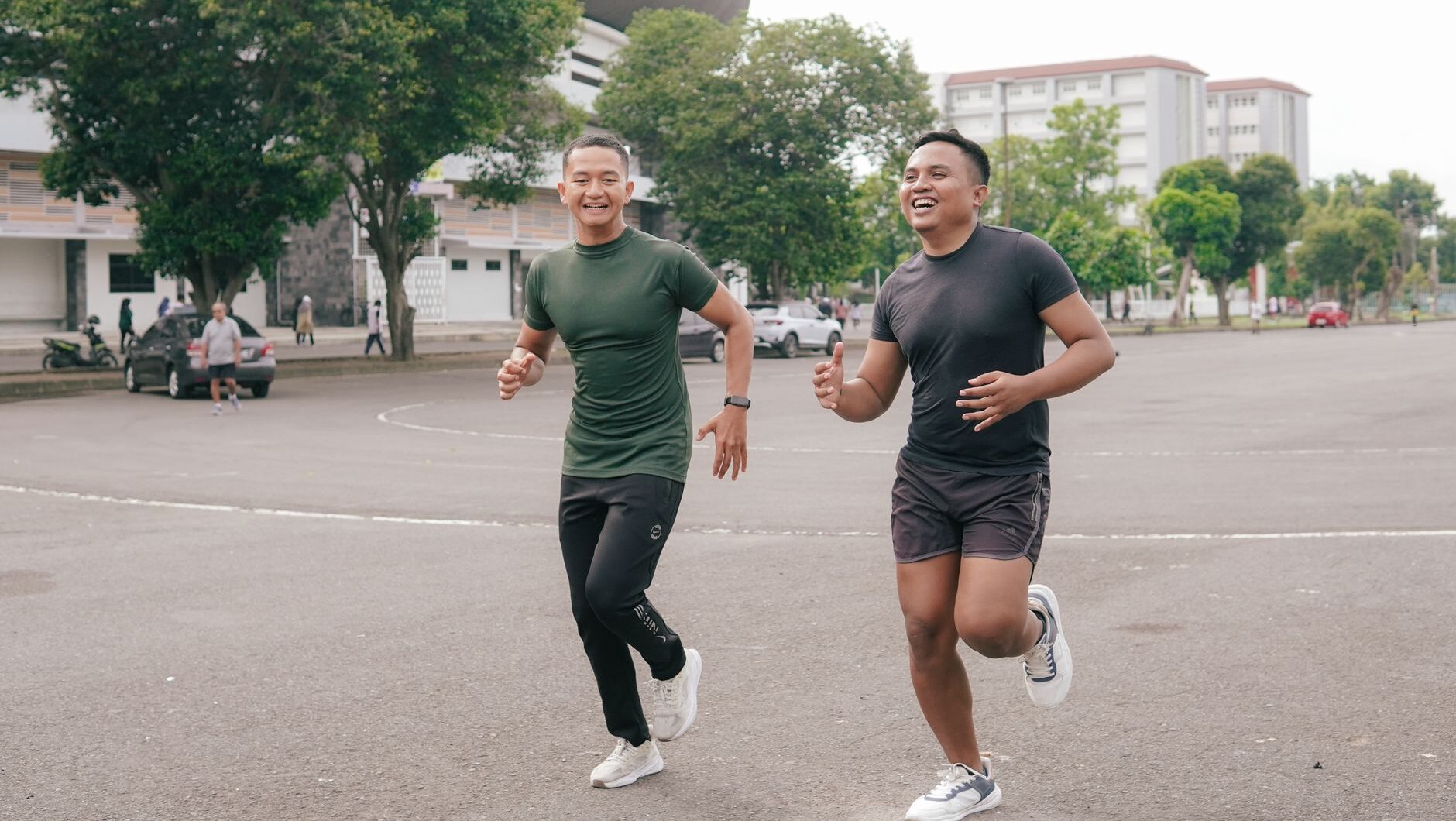 Dua pria sedang melakukan olahraga ringan dengan cara jogging bersama di area outdoor.