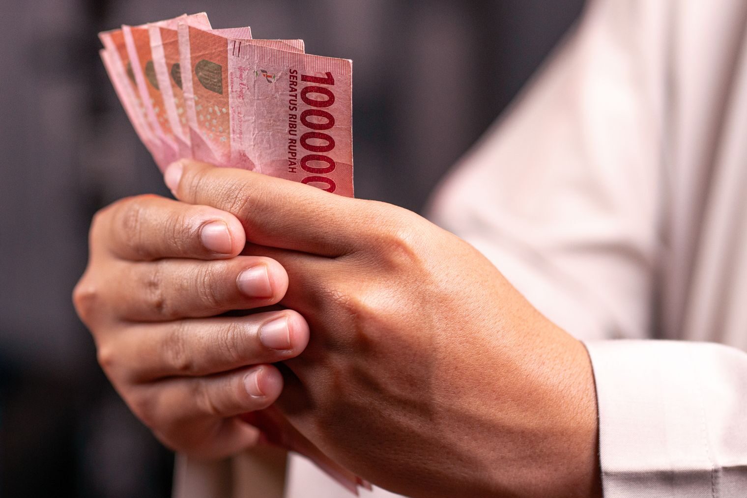 Seseorang memegang lembaran uang rupiah untuk mengatasi kebuntuan finansial bulanan.