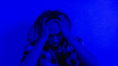 Person with long hair holding their head in distress, illustrating gejala depresi.