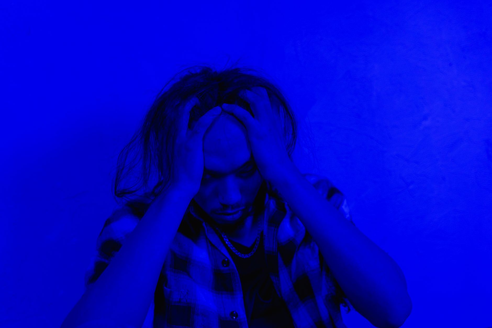 Person with long hair holding their head in distress, illustrating gejala depresi.