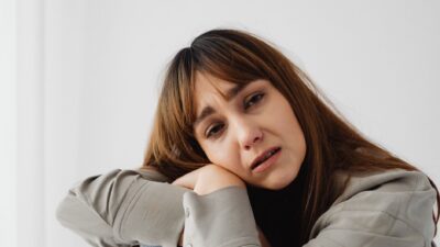 Seorang wanita muda tampak stres dan memegang kepala sebagai simbol gangguan mental.